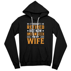 Black drawstring hoodie with humorous 'I Thought I Retired, But Now I Just Work for My Wife' text in orange and white.